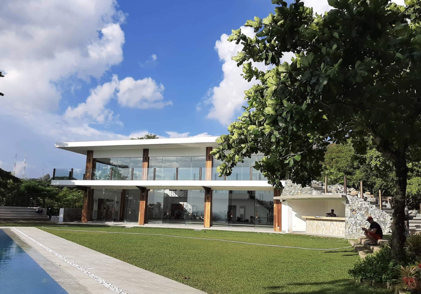 The Emerald reception venue, a modern glass pavilion beside a pool and lawn